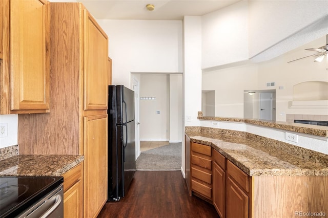 kitchen with dark hardwood / wood-style flooring, black fridge, light stone counters, ceiling fan, and range with electric stovetop