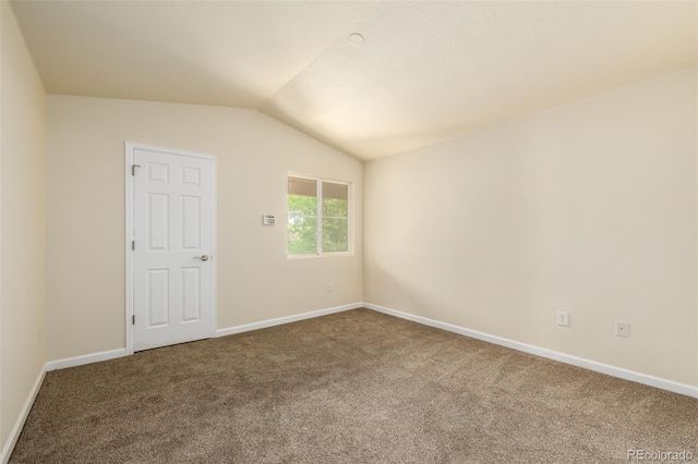 spare room featuring carpet flooring and vaulted ceiling