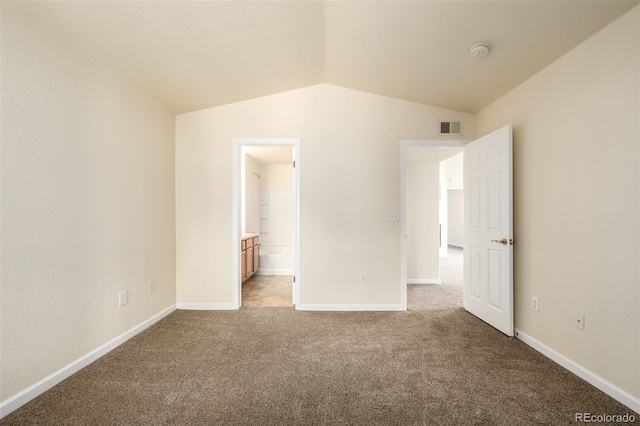 unfurnished bedroom featuring connected bathroom, carpet floors, and vaulted ceiling