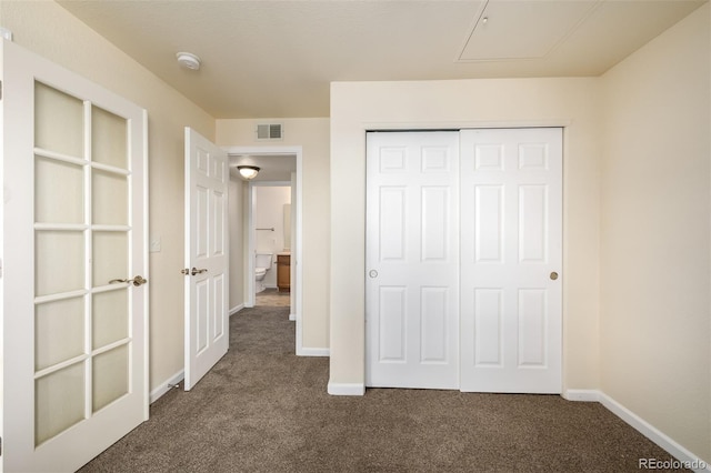 unfurnished bedroom with dark carpet and a closet