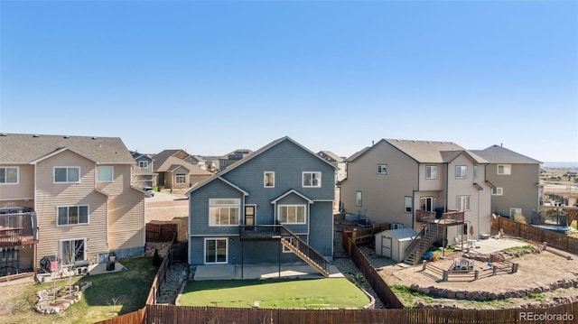 13135 Devils Thumb Pl, Peyton, CO 80831 - rear view of house featuring stairway, a fenced backyard, a residential view, and an outdoor fire pit