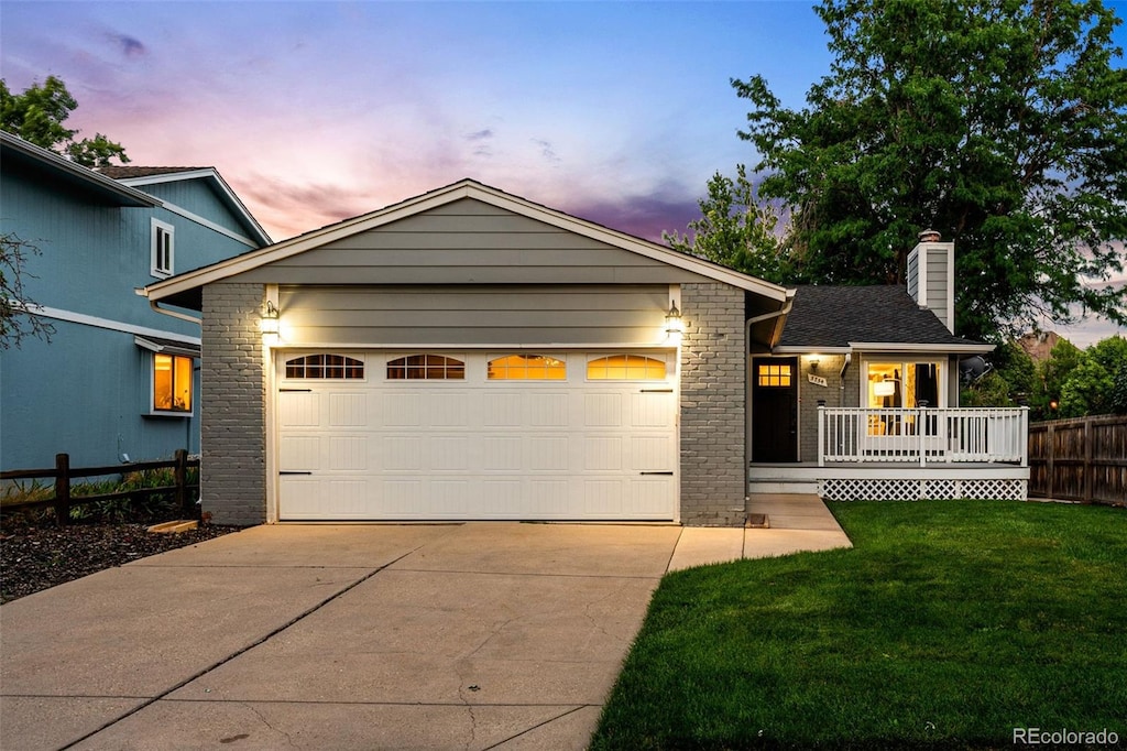 view of front of property with a garage, a yard, and covered porch