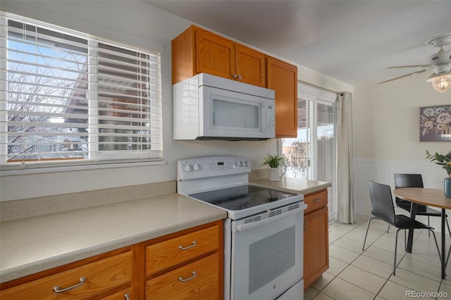 kitchen featuring ceiling fan, light tile patterned flooring, and white appliances