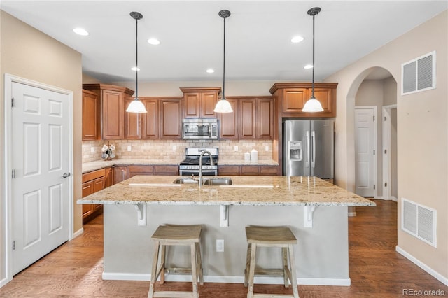 9530 Gray St, Westminster, CO 80031 - kitchen featuring appliances with stainless steel finishes, brown cabinets, backsplash, a kitchen bar, and recessed lighting