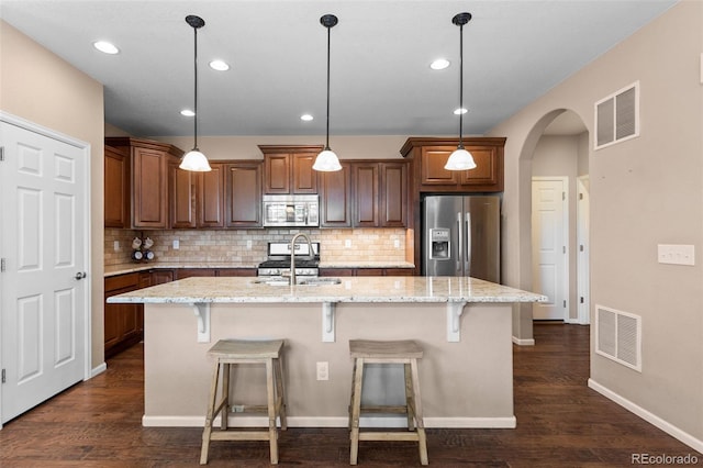 9530 Gray St, Westminster, CO 80031 - kitchen with appliances with stainless steel finishes, decorative backsplash, arched walkways, a center island with sink, and recessed lighting