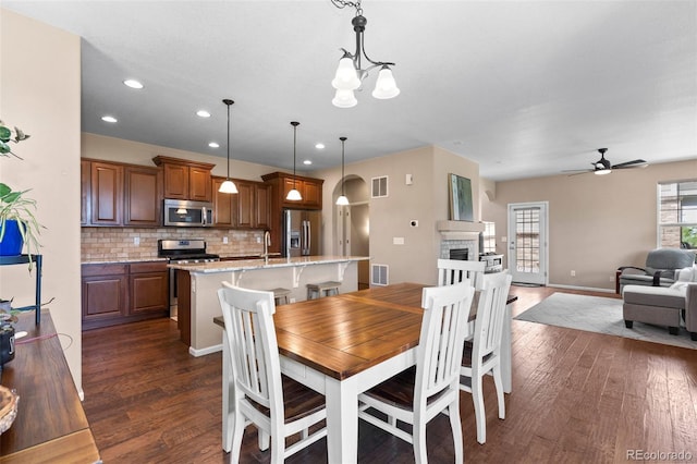 9530 Gray St, Westminster, CO 80031 - dining space with dark wood-style flooring, ceiling fan, recessed lighting, a fireplace, and a chandelier
