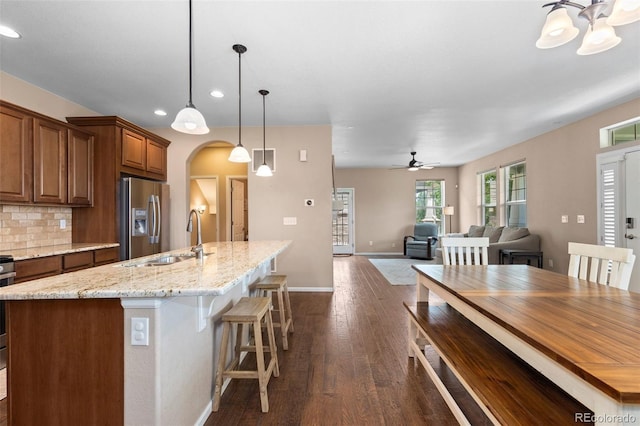 9530 Gray St, Westminster, CO 80031 - kitchen featuring stainless steel refrigerator with ice dispenser, recessed lighting, arched walkways, dark wood-style flooring, and an island with sink
