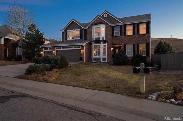 view of front of home featuring brick siding, driveway, a front yard, and fence