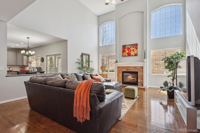 living room featuring dark wood-style floors, a fireplace, a high ceiling, and baseboards