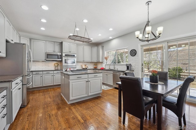 kitchen featuring a sink, dark countertops, a center island, appliances with stainless steel finishes, and decorative backsplash