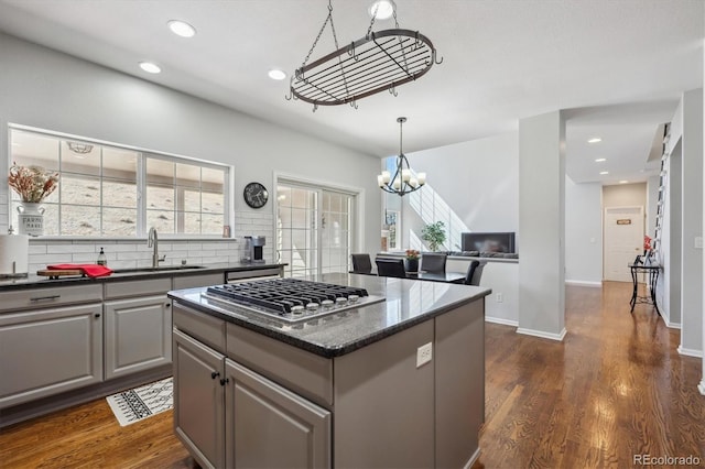 kitchen with stainless steel gas cooktop, gray cabinets, dark wood-type flooring, and a sink