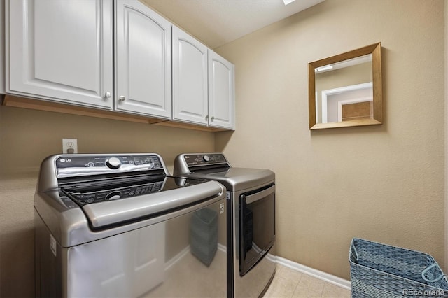 laundry room with light tile patterned floors, baseboards, cabinet space, and washing machine and clothes dryer