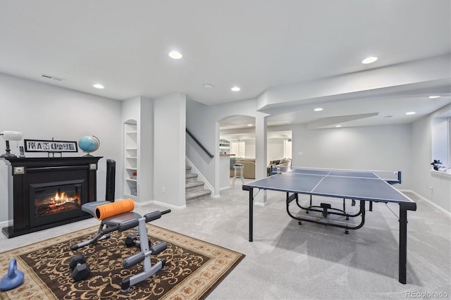 rec room featuring visible vents, baseboards, recessed lighting, arched walkways, and a glass covered fireplace