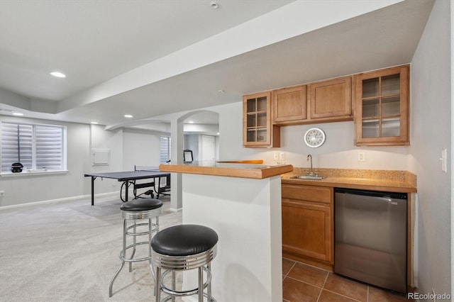 kitchen with a breakfast bar area, recessed lighting, a sink, glass insert cabinets, and fridge