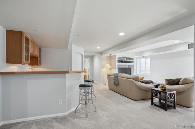 living room featuring recessed lighting, light colored carpet, built in shelves, and baseboards