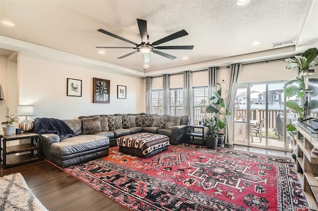 living room with ceiling fan, dark wood-type flooring, and a textured ceiling