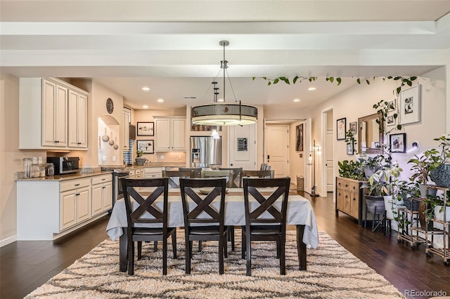 kitchen with a breakfast bar area, decorative light fixtures, a center island, appliances with stainless steel finishes, and dark hardwood / wood-style flooring