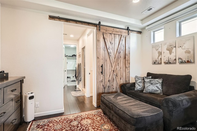 living area featuring a barn door and dark hardwood / wood-style floors