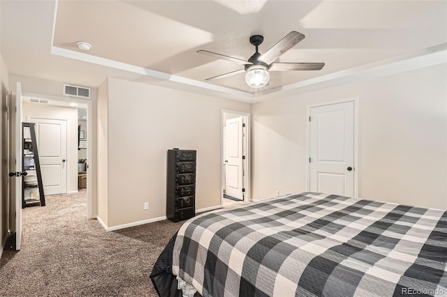 carpeted bedroom with a raised ceiling and ceiling fan