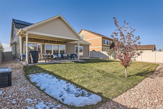 rear view of property with a yard, a patio, and solar panels