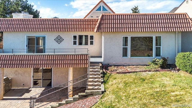 rear view of house featuring a lawn and a patio