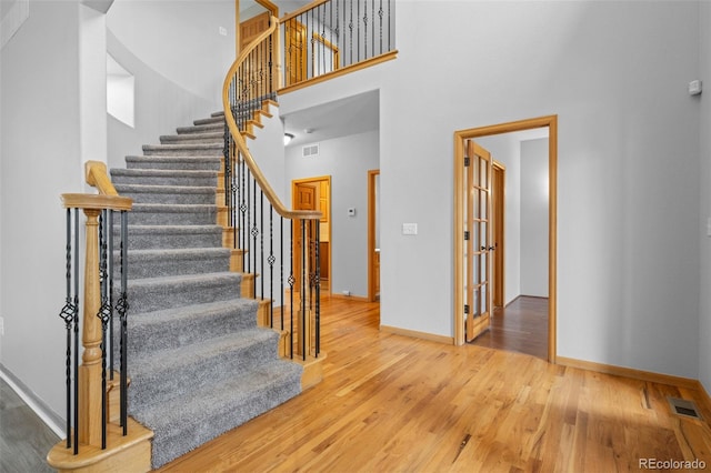 staircase with hardwood / wood-style flooring and a towering ceiling