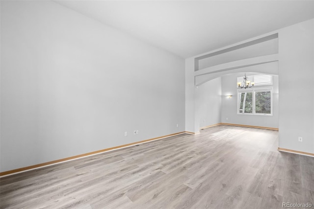 spare room featuring an inviting chandelier and light hardwood / wood-style floors