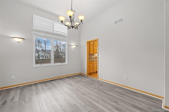 spare room featuring light hardwood / wood-style floors and a chandelier