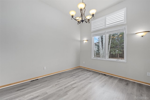 unfurnished room featuring an inviting chandelier and light wood-type flooring