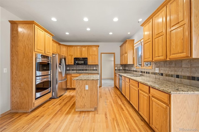 kitchen featuring light stone counters, sink, a kitchen island, and appliances with stainless steel finishes