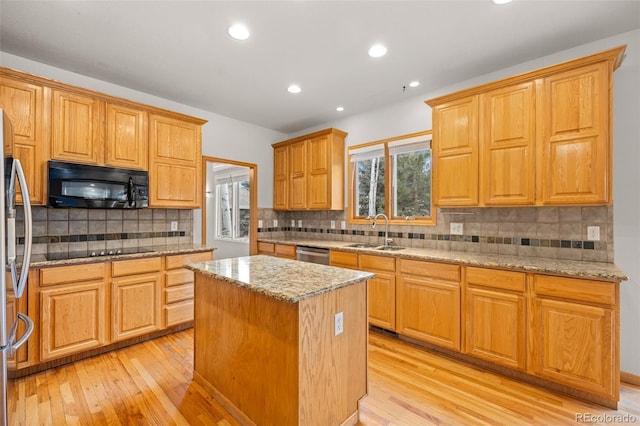 kitchen featuring a center island, sink, light stone countertops, and black appliances