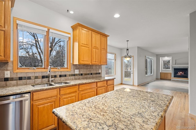 kitchen with sink, light hardwood / wood-style flooring, dishwasher, a kitchen island, and backsplash