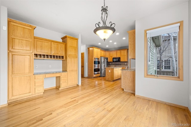 kitchen with stone countertops, decorative light fixtures, built in desk, light wood-type flooring, and stainless steel appliances