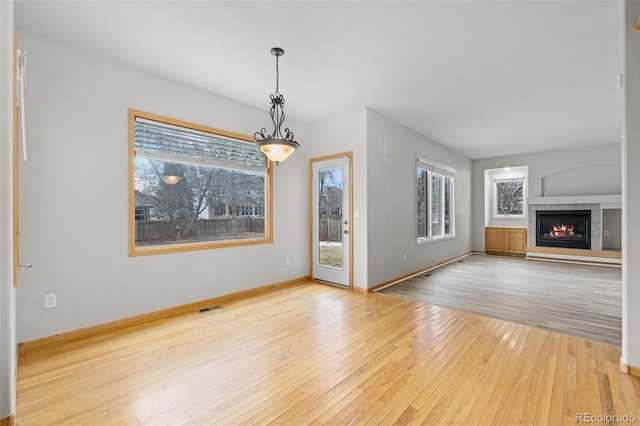 unfurnished living room with a tiled fireplace and light hardwood / wood-style floors