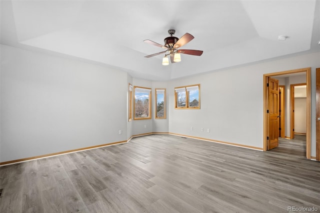 empty room featuring hardwood / wood-style flooring, a raised ceiling, and ceiling fan