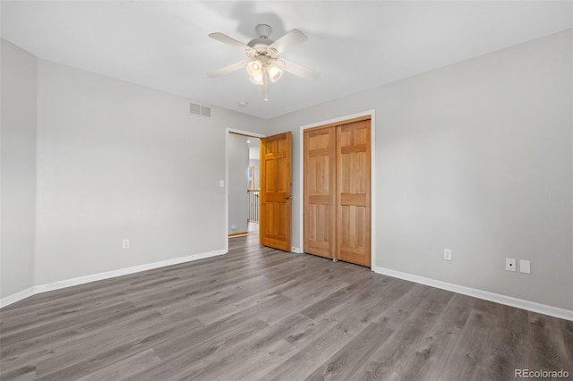 unfurnished bedroom featuring ceiling fan, wood-type flooring, and a closet