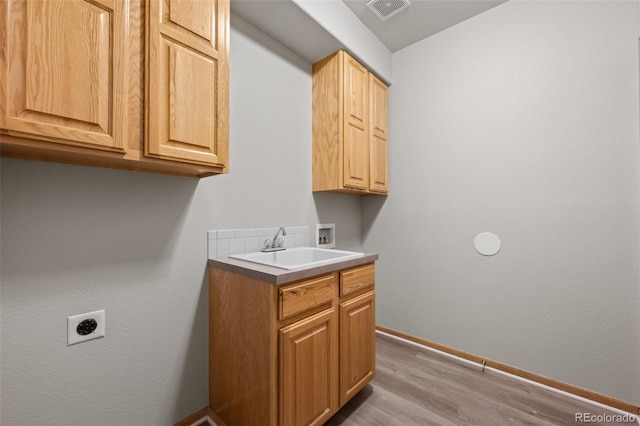 laundry area featuring sink, cabinets, light hardwood / wood-style flooring, hookup for a washing machine, and hookup for an electric dryer