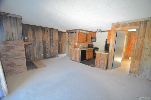 107 Peaks View Ct Unit 324, Blue River, CO 80424 - kitchen featuring black appliances, wooden walls, light countertops, light carpet, and brown cabinetry