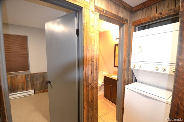 107 Peaks View Ct Unit 324, Blue River, CO 80424 - laundry area with a baseboard heating unit, estacked washer and dryer, light tile patterned floors, and wood walls