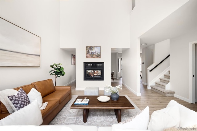 1530 S Quebec Way Unit 24, Denver, CO 80231 - living room featuring a multi sided fireplace, light wood-type flooring, stairs, and a high ceiling