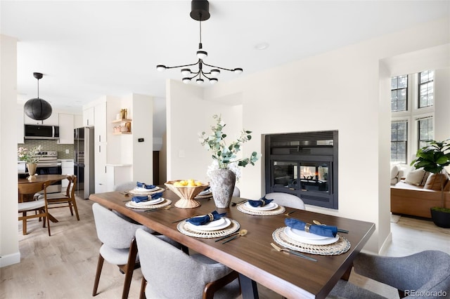 1530 S Quebec Way Unit 24, Denver, CO 80231 - dining area featuring a multi sided fireplace, a chandelier, and light wood-style flooring
