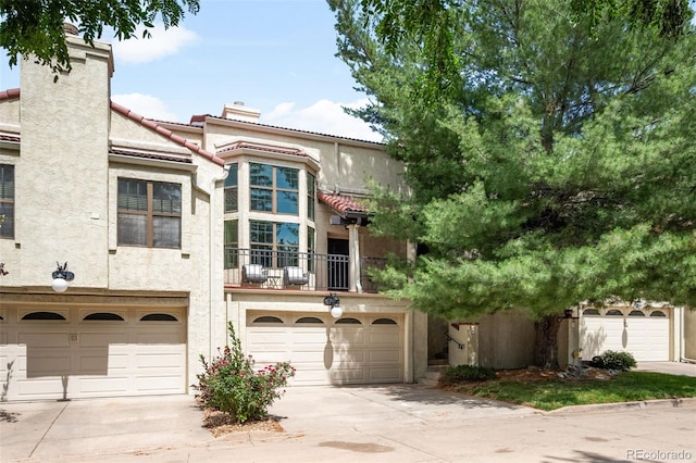 1530 S Quebec Way Unit 24, Denver, CO 80231 - view of front facade with a chimney, concrete driveway, stucco siding, and an attached garage