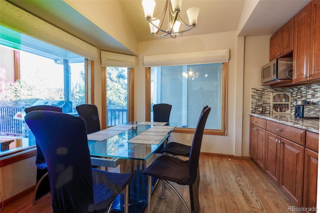 dining room with vaulted ceiling, a chandelier, and light wood-type flooring