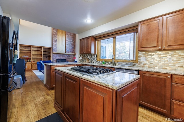 kitchen featuring light stone counters, appliances with stainless steel finishes, a center island, and light hardwood / wood-style flooring