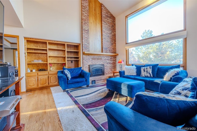 living room with a brick fireplace, light hardwood / wood-style flooring, and high vaulted ceiling