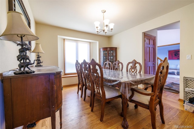 dining area featuring light wood-type flooring and an inviting chandelier