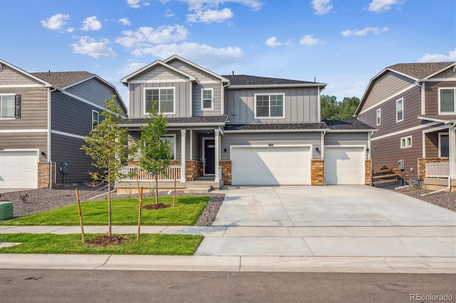 craftsman-style home with board and batten siding, a porch, driveway, stone siding, and a garage