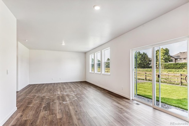 empty room featuring wood finished floors, visible vents, and baseboards