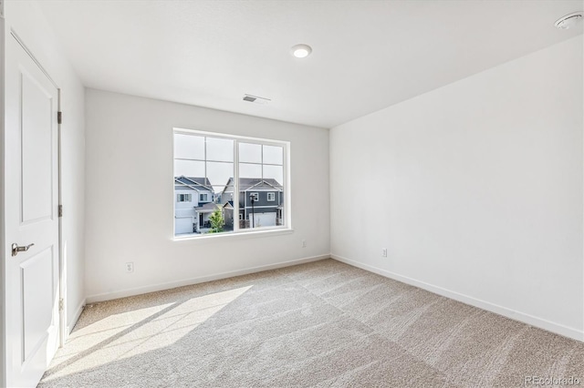 spare room featuring baseboards, visible vents, and light colored carpet