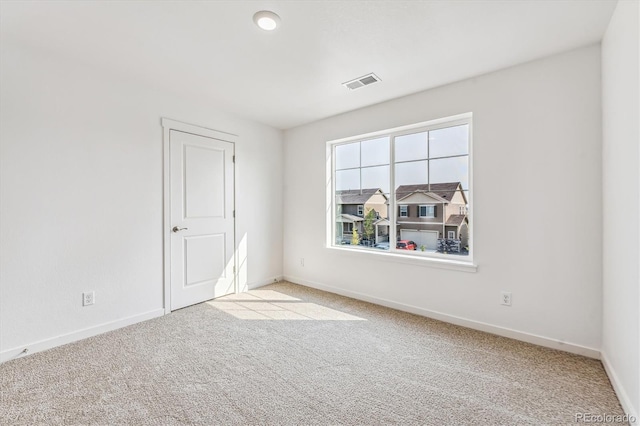 spare room with light carpet, baseboards, and visible vents